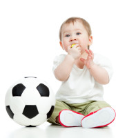 adorable baby football player with ball and whistle over white b