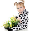 An adorable baby girl with a lap full of wild flowers, thinking in her cow costume.  On a white background.