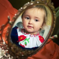 little baby-girl looks at herself in the mirror