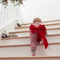 Toddler With Christmas Bow On Stairs In Pajamas