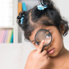 Indian girl peers at the camera through a magnifying glass